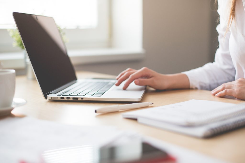 Woman with a laptop writing in a notebook